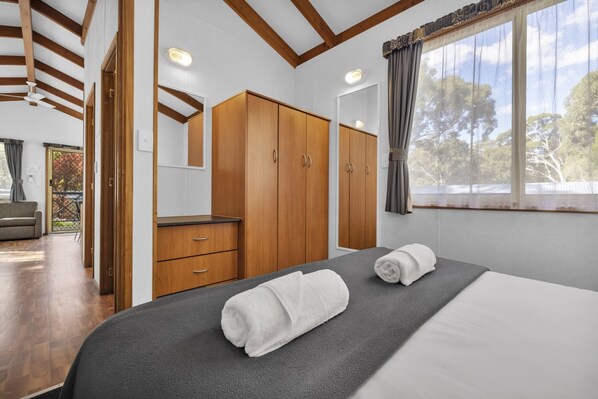 A bedroom with a bed, a wardrobe, a desk, and a window with curtains.