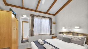 Een slaapkamer met een groot bed, een houten garderobe en een spiegel.