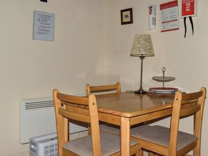 A dining area with a wooden table and chairs, a lamp, and a small decorative item on the table. - The Stable - UK49829 (Callington)