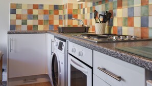A kitchen with a washing machine, a stove, and a tiled backsplash.