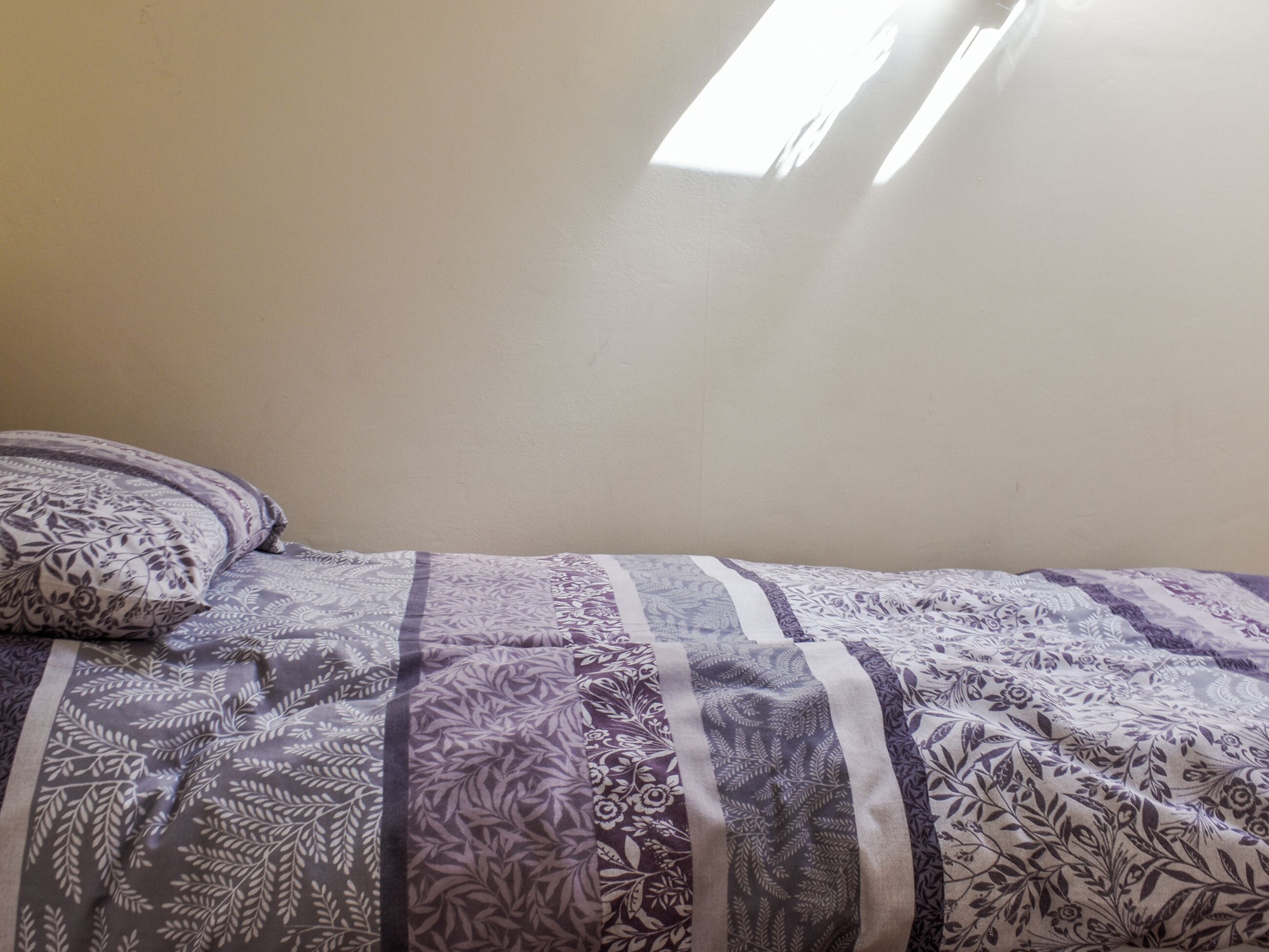 Une chambre à coucher avec un lit, une fenêtre et un mur uni.