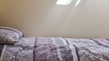 Une chambre à coucher avec un lit, une fenêtre et un mur uni.
