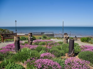 Une promenade en bord de mer, agrémentée de bancs, d’une rambarde et offrant une vue sur la mer.