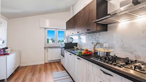 A modern kitchen with a gas stove, a coffee machine, and a view of the outdoors through a window. - Matta Apartment 400m From The Lake (Sirmione)
