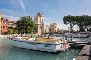 A boat docked at a marina with a castle in the background. - Matta Apartment 400m From The Lake (Sirmione)