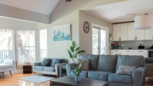 Uma sala de estar ampla com um sofá cinzento, uma mesa de centro e um vaso de planta.