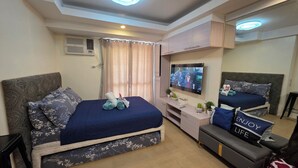 Habitació d'hotel moderna amb un llit gran, un escriptori, un televisor i un mirall.