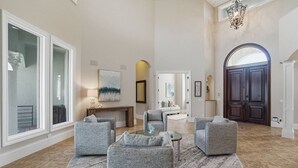 A spacious living room with a large window, a fireplace, and a grand door.
