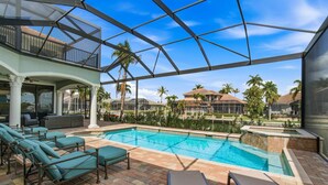 A pool area with lounge chairs, a covered seating area, and a view of surrounding buildings.