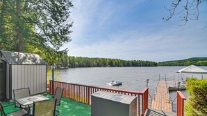 Järvenrantaterassi, jossa on ulkokalusteita, pieni varasto ja laituri, joka ulottuu veden päälle.