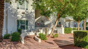 A building with a white exterior, a curved driveway, and a well-maintained garden with various shrubs and a tree. - 1 Mi to Tempe Beach Park: Well-Equipped Condo! (Tempe)
