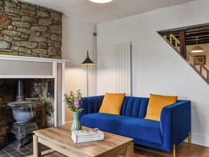 Una sala de estar acogedora con un sofá azul, una mesa de centro de madera, una pared de piedra y una chimenea.