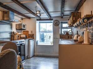 Eine Küche mit Holzbalkendecke, einem Fenster, einer Mikrowelle, einem Toaster und einem Wasserkocher.