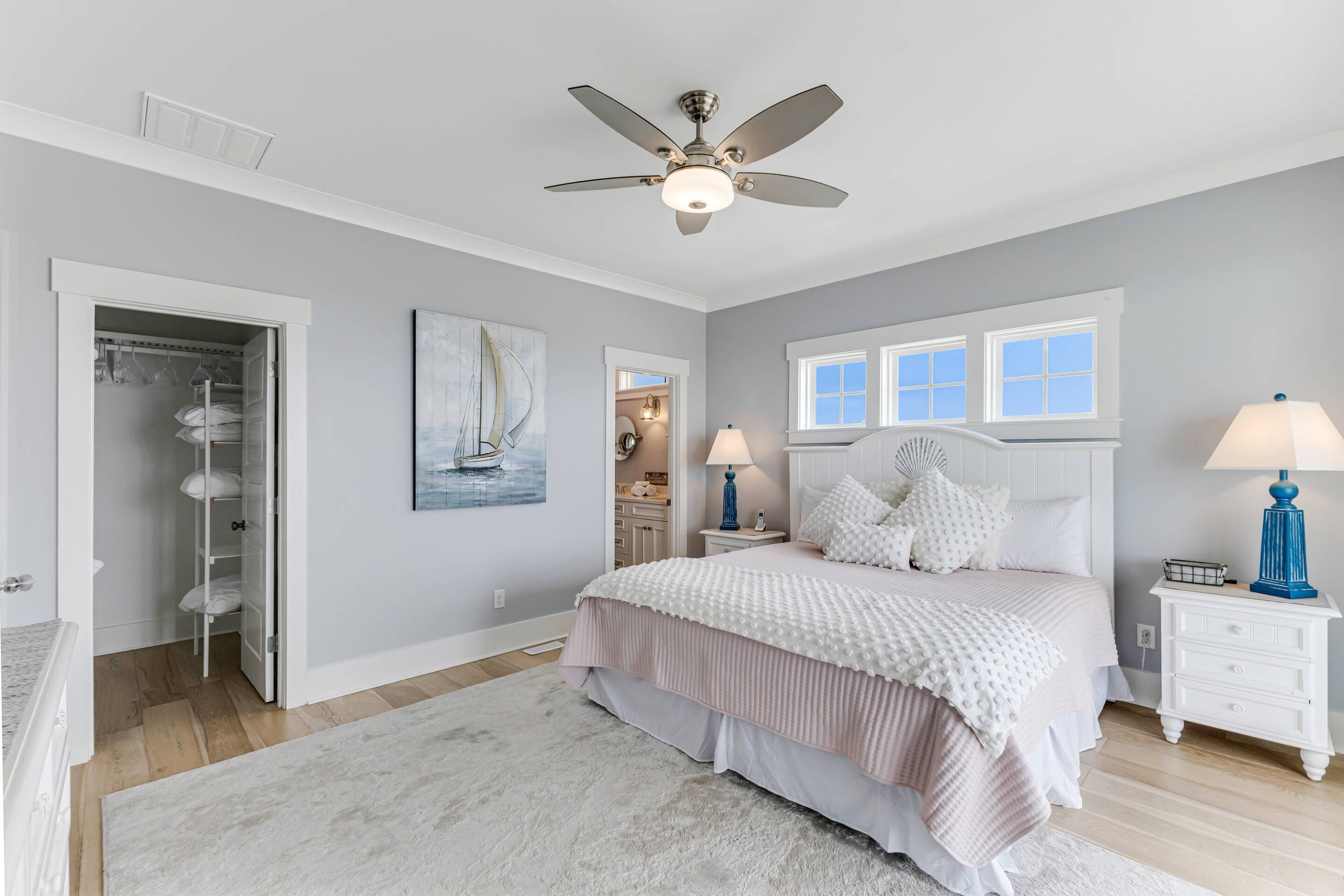 A bedroom with a bed, nightstands, a ceiling fan, a closet, and a window.
