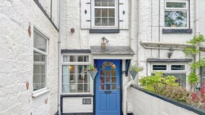 A narrow street with a blue door and white walls.