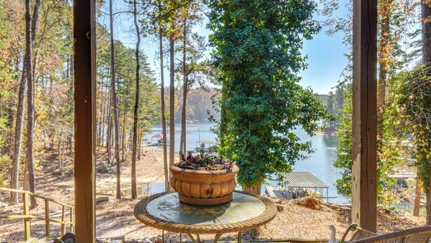 A covered outdoor seating area with wicker furniture, overlooking a lake and forest. - Home on Lake Lanier w/ Dock & Water Views (Gainesville)