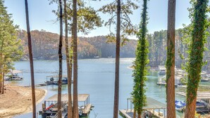A lakeside view with docked boats, surrounded by tall trees and a forested hillside. - Home on Lake Lanier w/ Dock & Water Views (Gainesville)