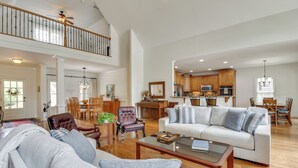 A spacious living room with a high ceiling, a dining area, and a kitchen with wooden cabinets. - Home on Lake Lanier w/ Dock & Water Views (Gainesville)