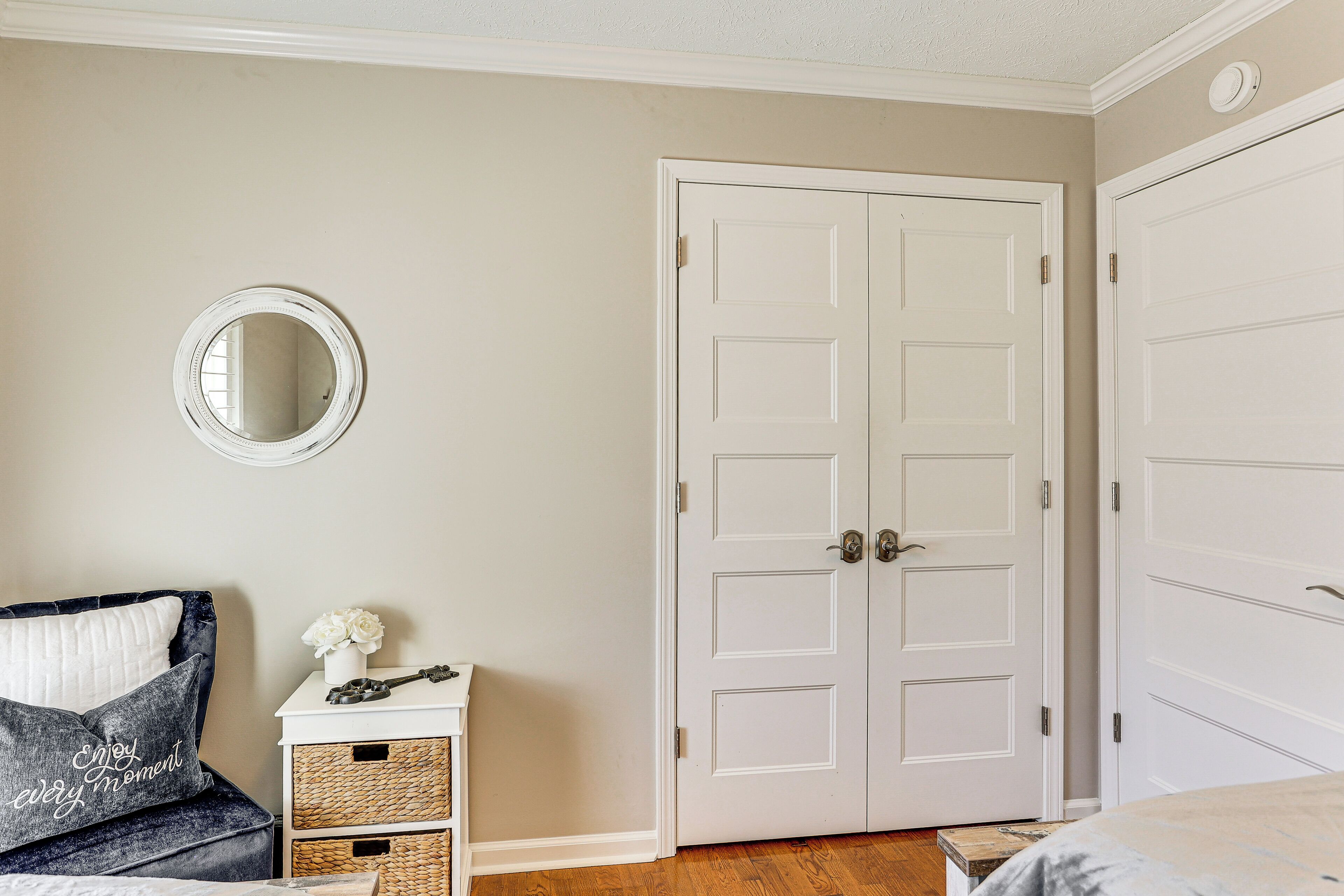 A bedroom with a bed, a dresser, a mirror, and a double door.