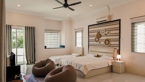 Un dormitorio moderno con dos camas, un ventilador de techo, un equipo de aire acondicionado y un ventanal con cortinas.