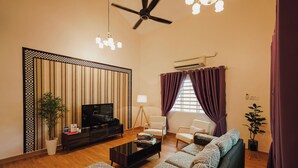 Una sala de estar moderna con un televisor de pantalla plana, un sofá, una mesa de centro y un ventilador de techo.