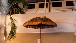 Un área de piscina con dos sillas de descanso y un paraguas de paja.