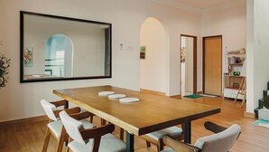 Un salón de conferencias con una mesa de madera, seis sillas, un ventilador de techo y un espejo grande en la pared.