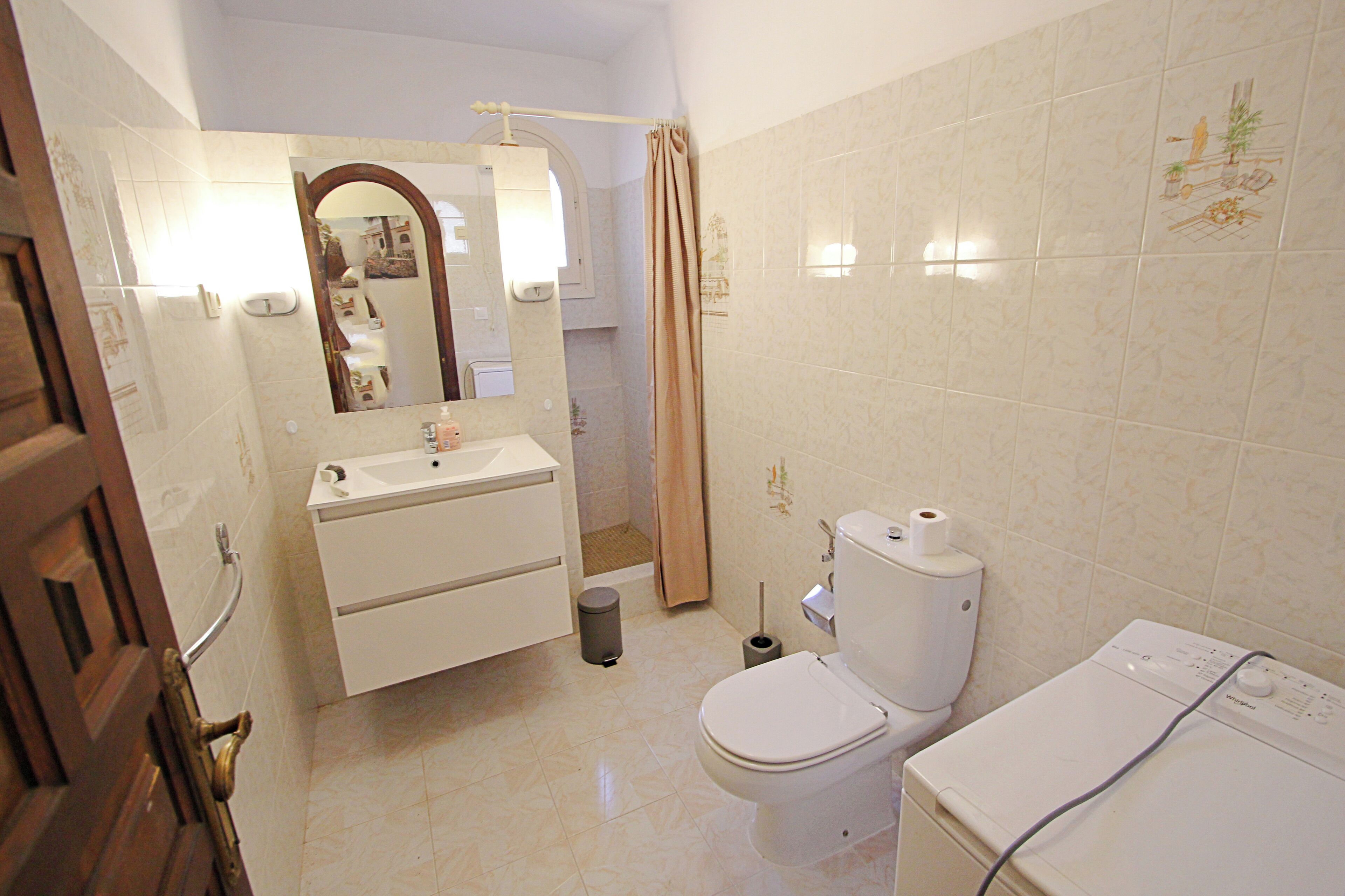 A bathroom with a toilet, sink, and mirror.