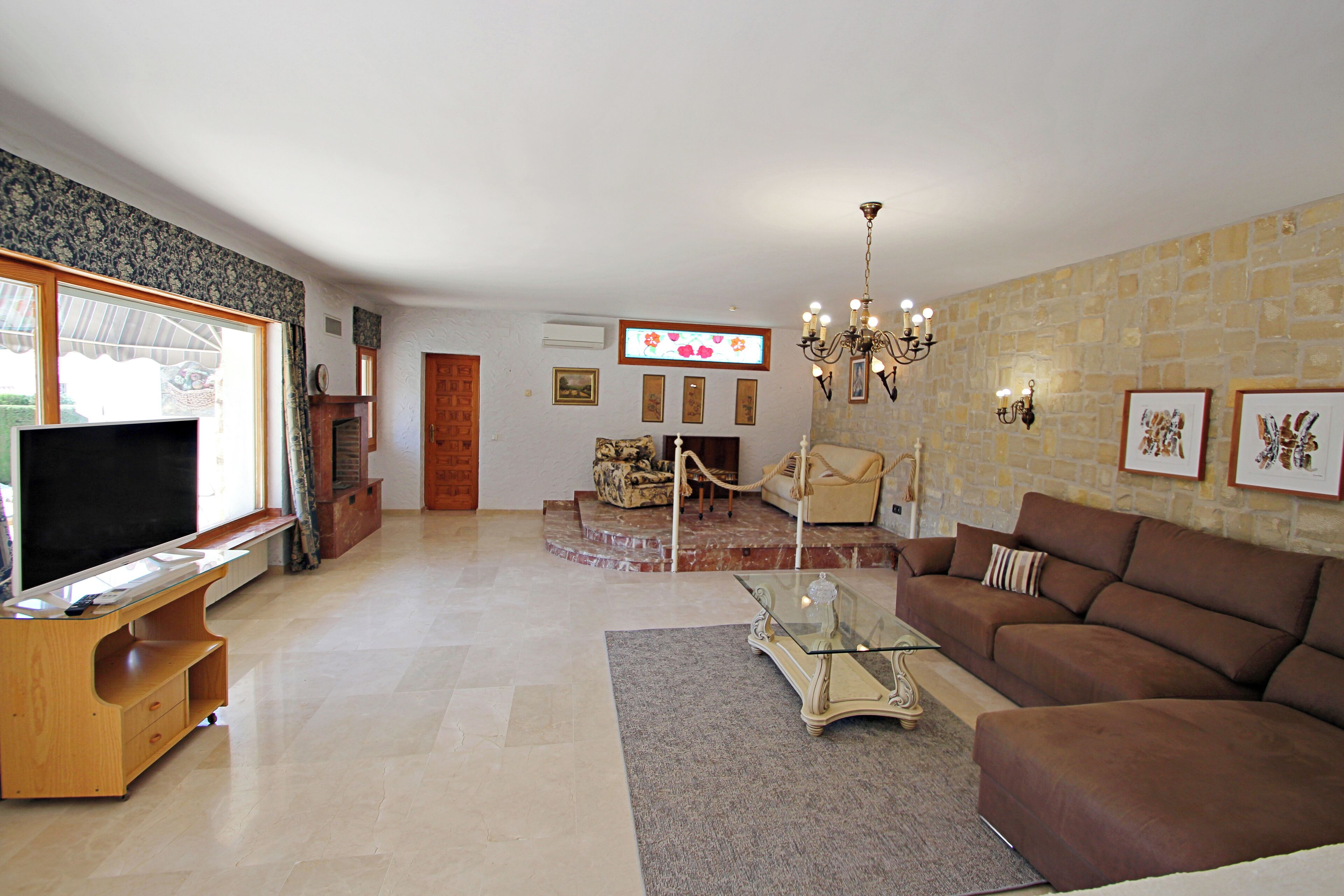 Una sala de estar con televisión, sofá y chimenea.