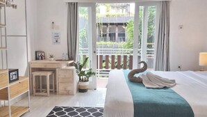 A bedroom with a bed, a desk, a chair, a potted plant, and a view of the outside. - The shortcut rooms (Canggu)