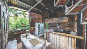 An open-plan kitchen with a wooden bar, a refrigerator, and various kitchen appliances. - The shortcut rooms (Canggu)