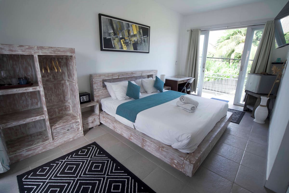 A bedroom with a bed, a desk, a wardrobe, and a window with curtains.