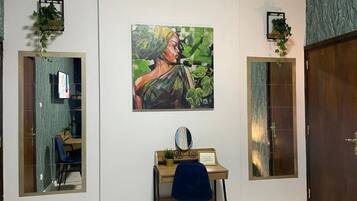 A room with a desk, chair, and a painting on the wall.