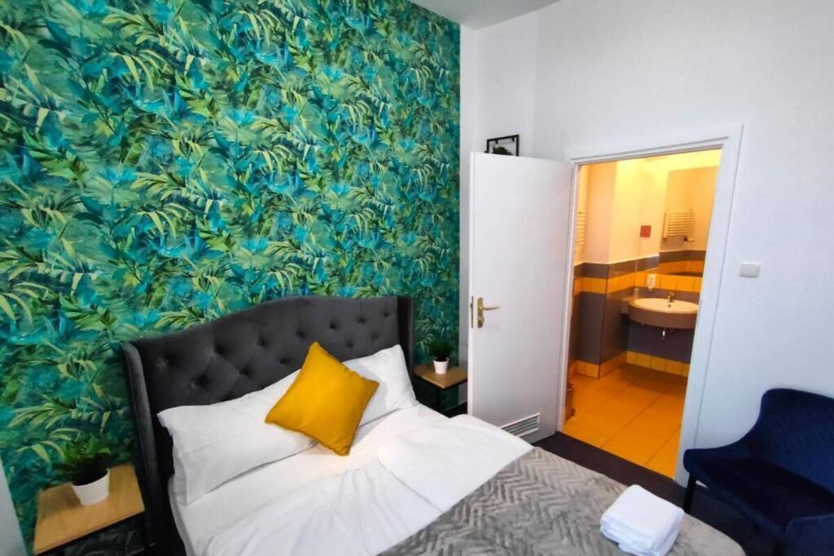 Ein Hotelzimmer mit einem Bett, einem blauen Stuhl und einem durchgehenden Türbogen sichtbarem Badezimmer.