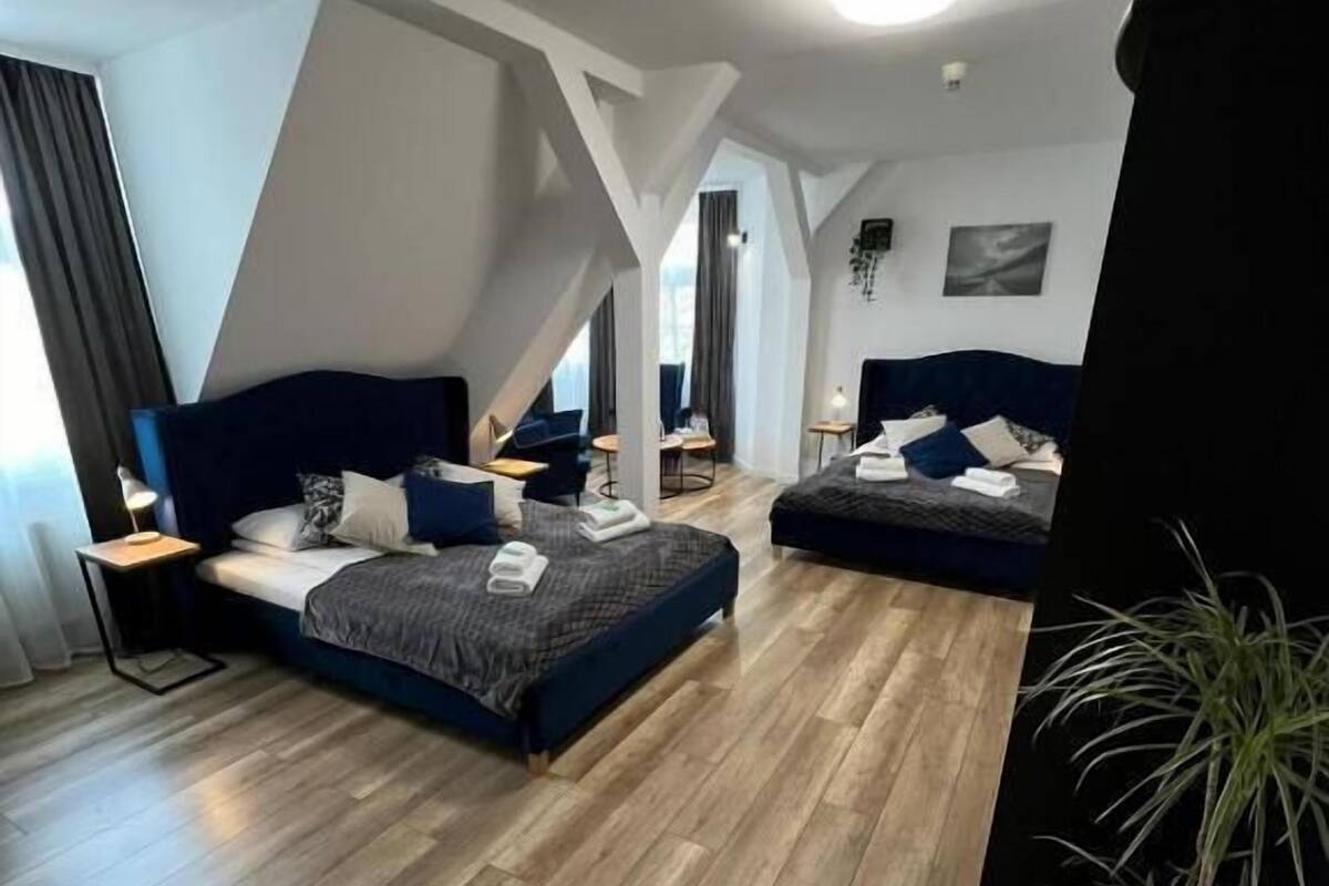 Ein modernes Schlafzimmer im Loft-Stil mit einem großen Bett, einem kleineren Bett und einem Schreibtisch.