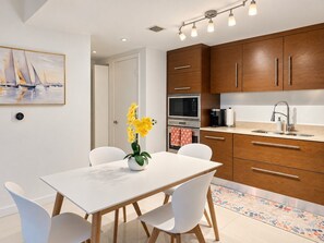 A modern kitchen with wooden cabinets, a white dining table, and chairs.