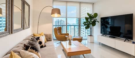 A modern living room with a sofa, armchair, coffee table, and a TV.