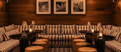 A living room with striped sofas, round tables, and wall-mounted lamps.