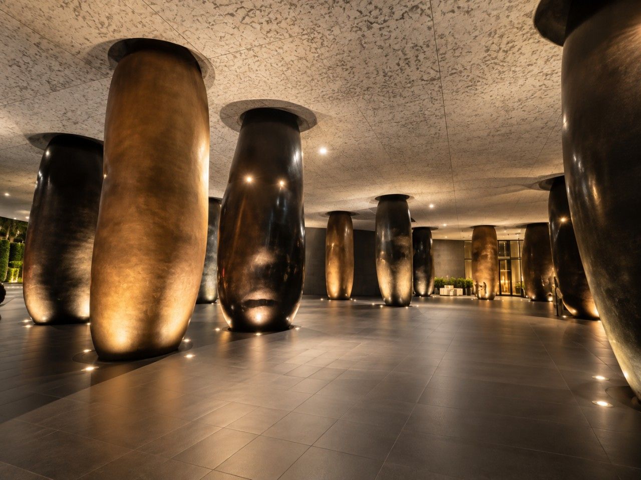 A spacious lobby with large, metallic cylindrical columns and a polished floor.