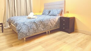 A bedroom with a bed, nightstands, a lamp, and a window with curtains. - Two bed flat cobh (Cobh)