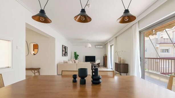 A dining area with a wooden table, four chairs, and three pendant lights.