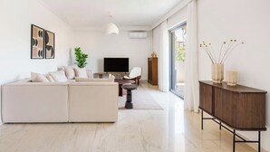 A modern living room with a sectional sofa, a flat-screen TV, a coffee table, and a cabinet.