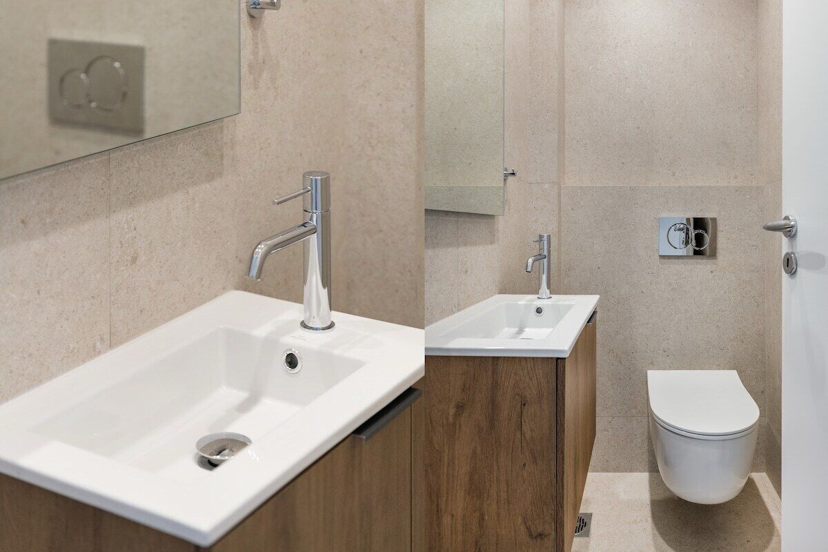 A modern bathroom with a large sink, a mirror, and a toilet.
