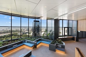 Un intérieur moderne avec de grandes fenêtres, des coins salon et une vue sur le paysage urbain.