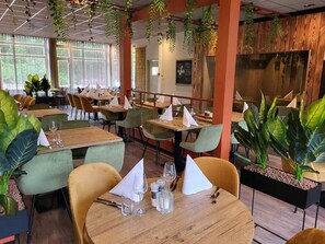 Enjoy dining in a warm and inviting atmosphere with comfortable seating and lush greenery.