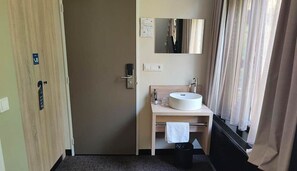 Cozy retreat with a comfortable bed, bedside table, and modern sink.