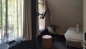Enjoy a peaceful retreat with a forest view from this cozy room featuring a single bed, flat-screen TV, and comfortable seating area.