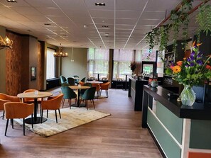 Relax in our inviting lobby with a central seating area, reception desk, and lush greenery.