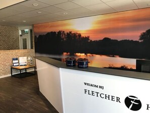 Experience a serene atmosphere in our reception area, featuring a scenic mural and a digital display.