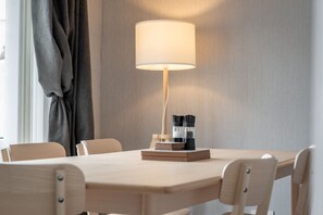 Ein Holztisch mit Lampe, Büchern und einer Kaffeemaschine.